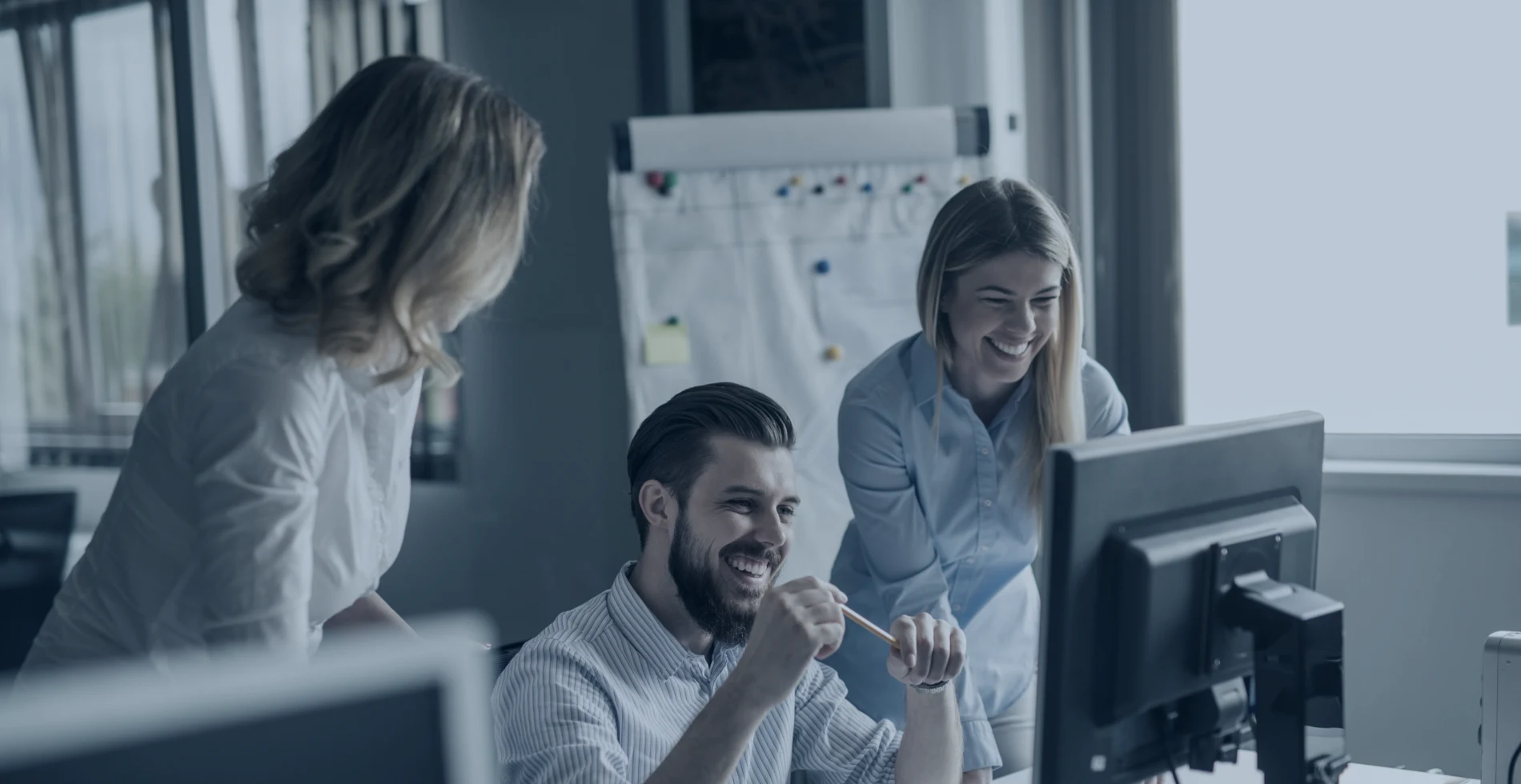 Smiling team of professionals collaborating on a computer project in an office