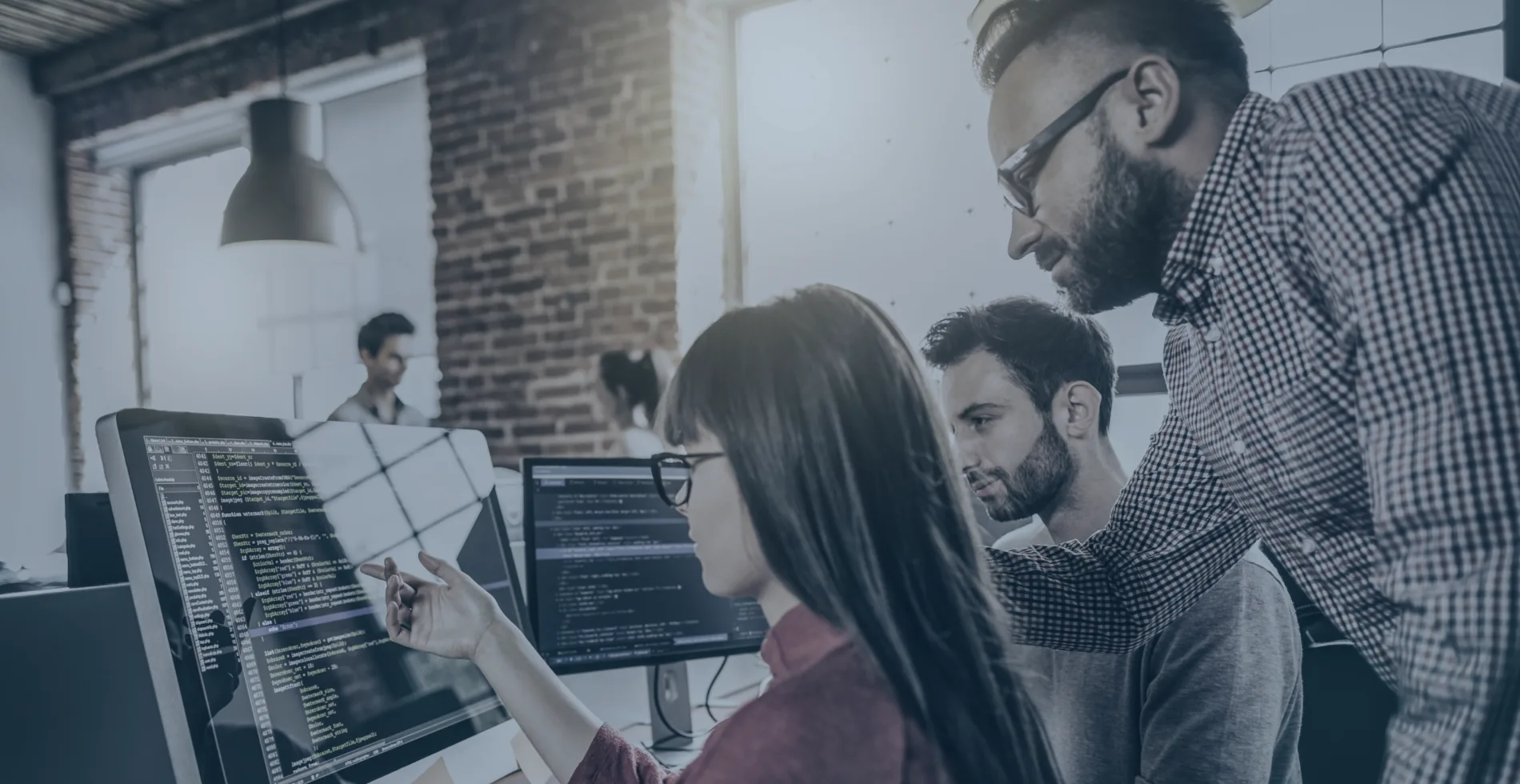 Software development team collaborating and coding at modern office workspace